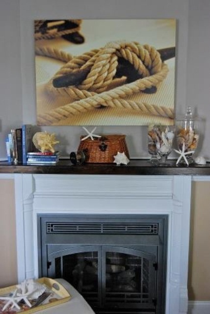 a simple beach mantel with starfish and seashells, large jars with seashells and starfish and a rope artwork over it