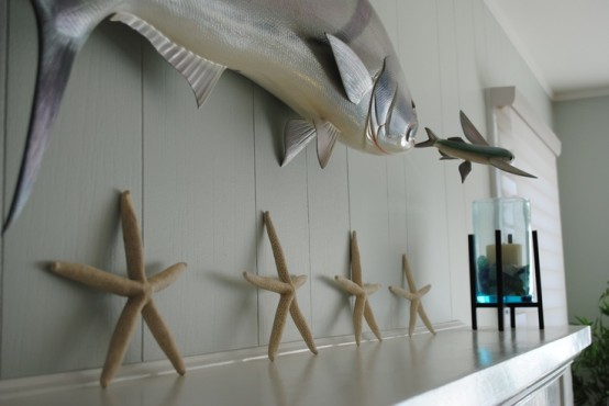 a beach mantel with starfish, a candle in a blue candleholder and some fish over the mantel is very cool