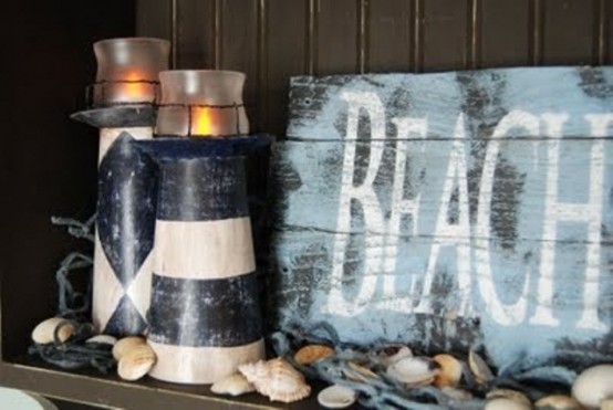 a mantel covered with seashells, beacon candle lanterns and a blue sign that you can DIY