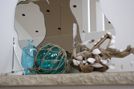 a cool beach mantel with a blue bottle and a blue glass float, a piece of driftwood with seashells attached