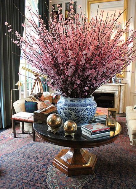 bold pink cherry blossom branches in a blue vase make a bold statement in the space and bring a spring feel to it