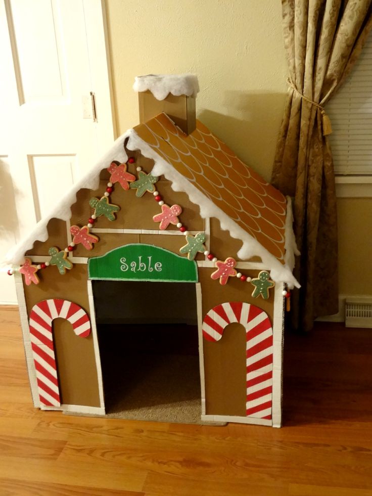 a gingerbread style dog house of cardboard with candy canes and gingerbread men garlands is a cool idea for the holidays