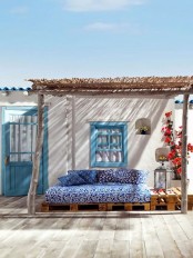 a small Mediterranean outdoor space – a blue printed sofa under a roof, colorful blooms and Moroccan lanterns is amazing