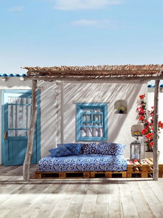 a small Mediterranean outdoor space - a blue printed sofa under a roof, colorful blooms and Moroccan lanterns is amazing