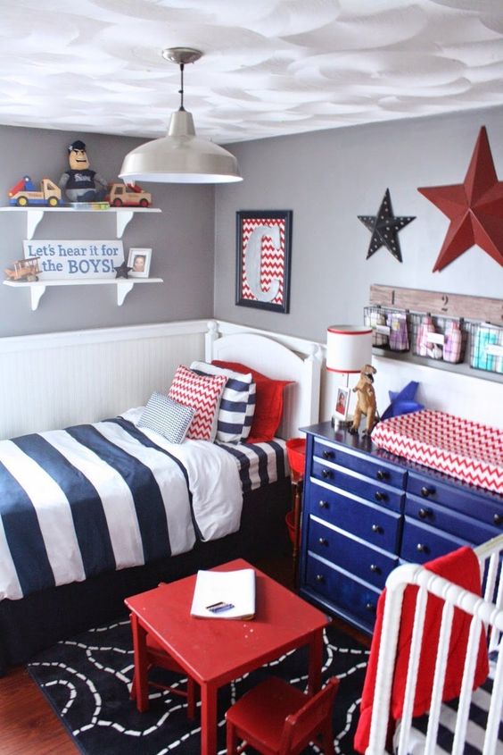 a bright nursery in blue, red, white and grey, with stars, colorful furniture and bedding and lots of toys