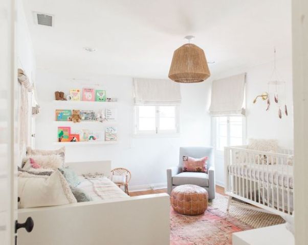 a neutral shared space with white beds, white Roman shades, a leather ottoman, a wicker lampshade and floating shelves