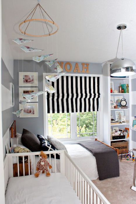 a grey and white nursery, a striped Roman shade, built-in shelves, matching beds and a mobile