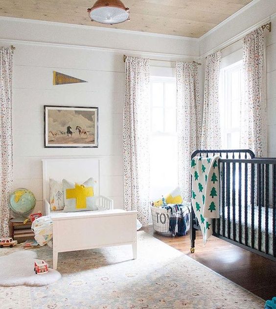 a neutral shared space with printed curtains, contrasting beds and some bright touches here and there