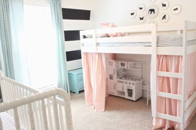 a simple shared space done with a striped wall, two matching beds, pink and blue curtains