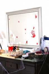 an oversized mirror in a silver frame with bloody hand marks and a jar full of blood will hint on the theme of your party in a delicate way