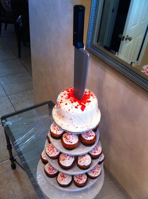 a stunning bloody drip cake topped with a knife on top and with matching cupcakes is a lovely idea for a Dexter-inspired party at Halloween