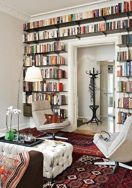 a doorway wall fully covered with dark open bookshelves is a cool idea to store all your books without sacrificing any floor space and to give a cozy library feel to the room