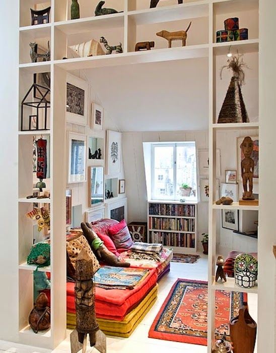 an open shelving unit placed in the doorway to separate the living room and the rest of the house and display some objects at the same time