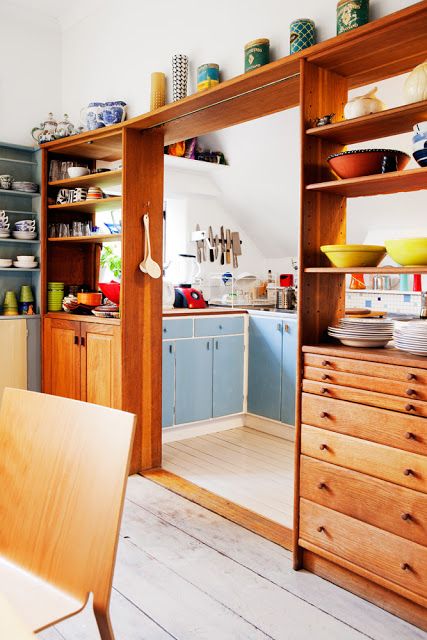 a pretty mid-century modern stained shelving unit with drawers separates the kitchen and the dining space and gives some storage space to both areas