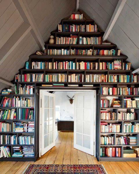 an attic room with a doorway and a wall fully covered with bookshelves is a smart idea to store all the books without takign a lot of floor space


