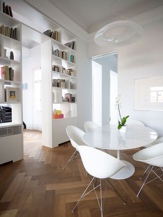 a shelving unit with a doorway placed in the center of the room to divide the dining zone and the living room is a smart idea with plenty of storage