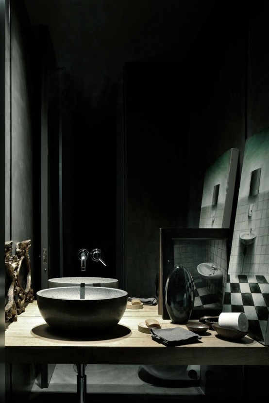 a creative Gothic bathroom with black walls, a mirror wall, a stone bowl sink, a floating vanity and some artworks