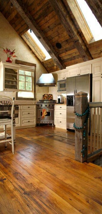 a barn kitchen with a wood clad ceiling, white vintage cabinets, light-stained floor and vintage stools