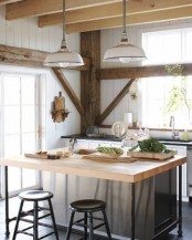 a pretty neutral barn kitchen with white planked walls, rough wooden beams, pendant lamps, a metal kitchen island with stools