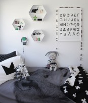 a Scandinavian kid’s room with a bed, monochromatic bedding, hexagon-shaped shelves and toys and art that match the space color scheme