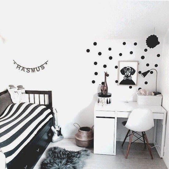 a black and white Nordic kid's room with a black bed and striped bedding, a white desk and a chair, a polka dot accent and some artwork