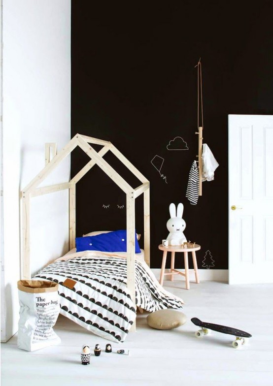a stylish Scandinavian kid's room with a black accent wall, a wooden house-shaped bed, graphic bedding, a wooden a side table with a Miffy lamp and a basket for storage