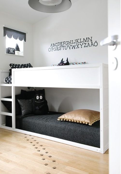 a black and white Nordic kids' room with a white bunk bed, black bedding, an accent on the wall and some pretty decor