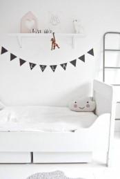 an airy and ethereal Scandinavian kid’s room with a white bed and drawers, an open shelf and a ladder and a black banner