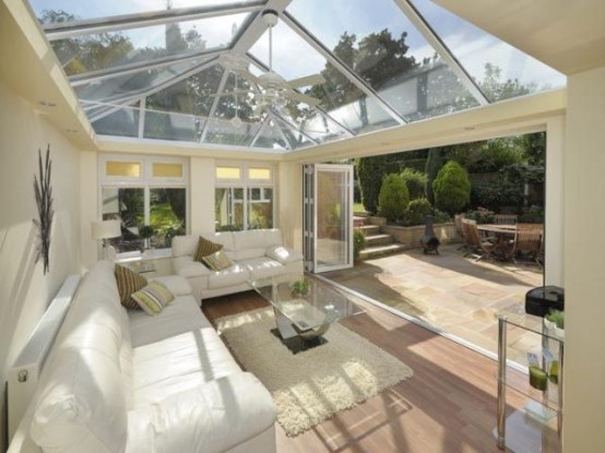a neutral contemporary attic sunroom with stylish white furniture and glass tables and a glazed ceiling and a wall