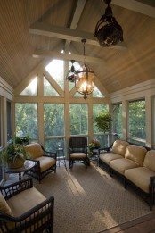 a vintage-inspired sunroom done in tan and beige, dark rattan furniture and pendant lamps and chandeliers