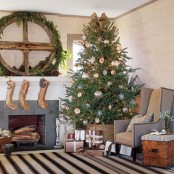 an oversized fir branch wreath, burlap stockings, a Christmas tree with metallic ornaments in a basket for a rustic holiday feel in the space