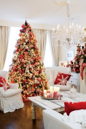 a super bold red and white Christmas living room with a bright Christmas tree with lights and red and white ornaments, stockings, pillows and a garland with bright red decor