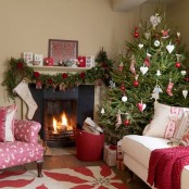 a Christmas tree with red and white ornaments, a garland with red blooms and gift boxes make the space feel Scandinavian and holiday-like