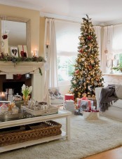 a fir garland with pinecones, a Christmas tree with lights, red and white ornaments create a holiday ambience in this living room