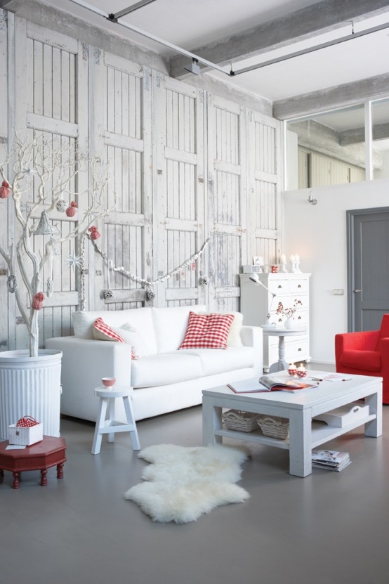 a white and red Christmas living room with a white tree with red ornaments in a pot, a white garland with whitewashed pinecones, plaid and red linens here and there