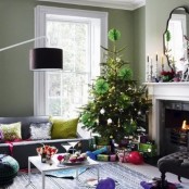 a contrasting living room with bright touches and a Christmas tree with lights, metallic ornaments and green paper ornaments is very chic and cool