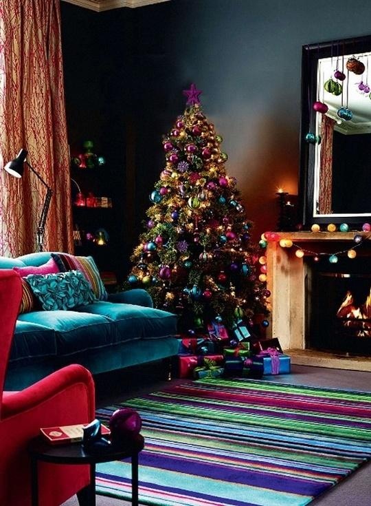 a moody living room with colorful textiles and a colorful Christmas tree with lights, with colorful ornaments on the mirror and mantel is very bold and cool
