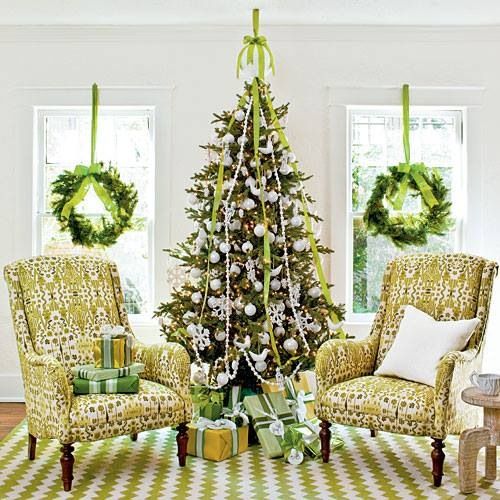evergreen wreaths with bright green ribbons, a Christmas tree with bold green ribbons and white ornaments for a holiday feel in the space