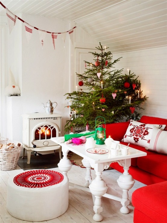 a red and white Scandinavian Christmas living room with matching holiday decor - a Christmas tree with red and white ornaments, a red and white fabric banner over the space