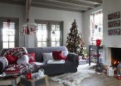 red and white Scandinavian Christmas decor with a pretty chandelier, a heavily decorated Christmas tree, red and white pillows and blankets, lanterns and artworks