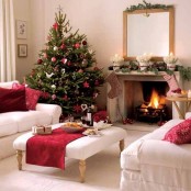 refined neutral Christmas living room with a tree decorated with red and white ornaments, stockings, colorful pillows and other stuff