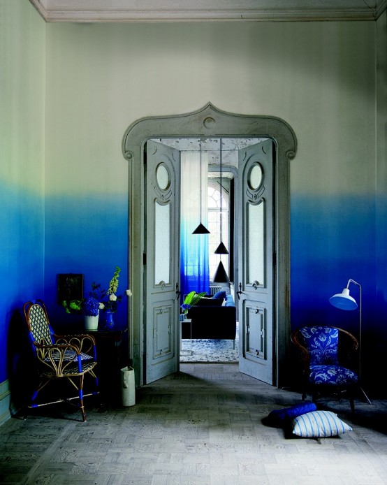a refined entryway with ombre blue walls, bold blue rattan chairs and floor lamps and refined vintage doors