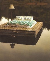 a floating platform with a bed with printed bedding and a floor lamp is a very creative place to fall asleep