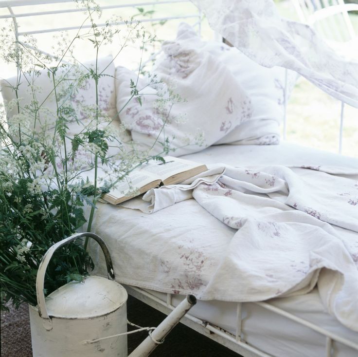 a white metal bed with floral bedding, greenery and a watering can are all you need for an outdoor shabby chic bedroom