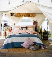 an outdoor bed under a canopy, with a bed with lots of pillows, a hat hanger and a crate nightstand for a rustic touch