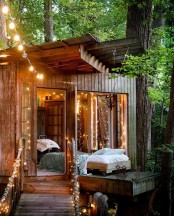 a wooden shed with lights and a low bed with neutral bedding is a lovely outdoor oasis to have a rest or a sleep