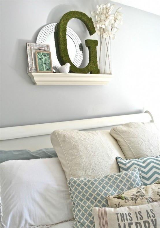 a pastel blue bedroom with white furniture, a mirror, moss, artworks and printed bedding