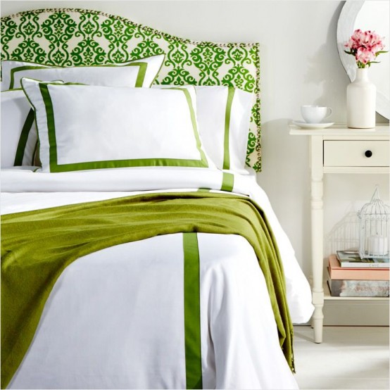 a colorful spring bedroom with white furniture, a green printed bed, green and white bedding and blooms