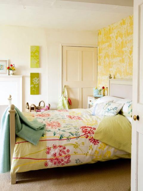 a colorful spring bedroom with neutral furniture, colorful bedding, floral prints and wallpaper on the wall is cheerful