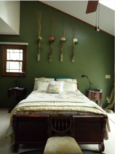 a vintage bedroom with dark wooden furniture, floral bedding, floral arrangements in vases and pendant lamps